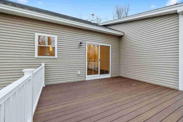 Completed residential deck with brown decking, white railing, and access through sliding glass doors