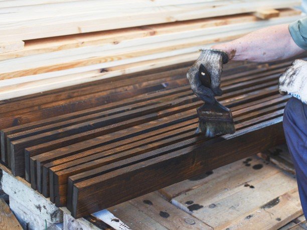 A professional worker is working on wood staining in plank.