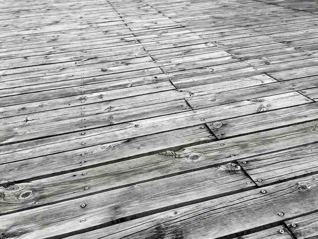 Damaged and weathered wood deck boards showing cracks, gaps, and surface wear before deck repair