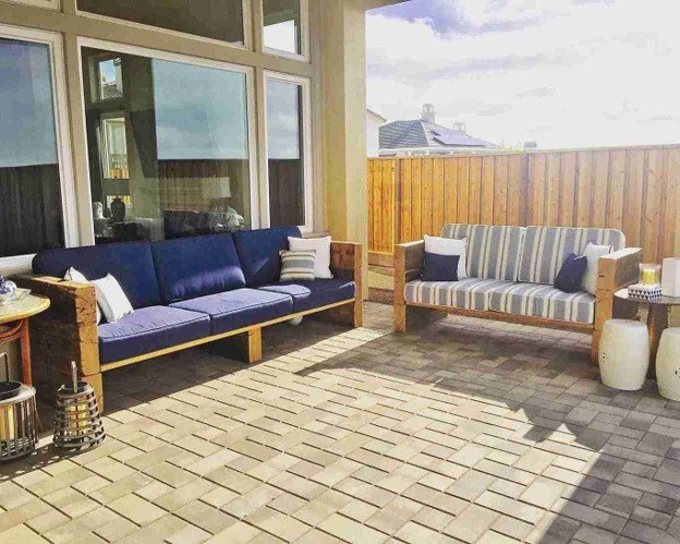 Completed custom backyard deck with wood pergola, outdoor seating, landscaping, and dining space