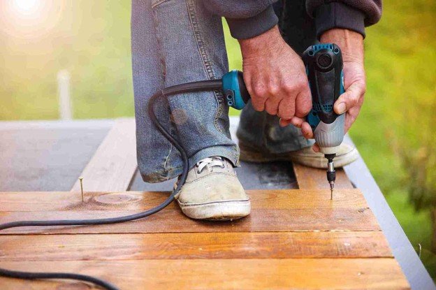 A worker professional using drilling tool for remodeling old deck