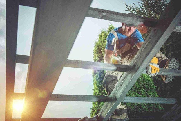 A professional working on pergola construction while the sun is up.