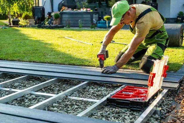 Contractor installing Trex composite deck boards over a metal frame in a residential backyard.