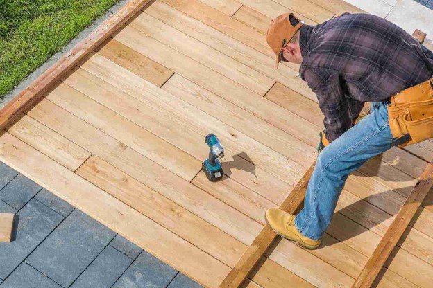 Deck contractor installing wood boards during a custom residential deck construction project
