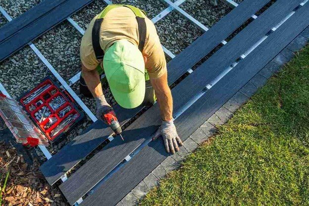 Contractor fastening composite deck boards to a metal frame during a Trex deck installation.