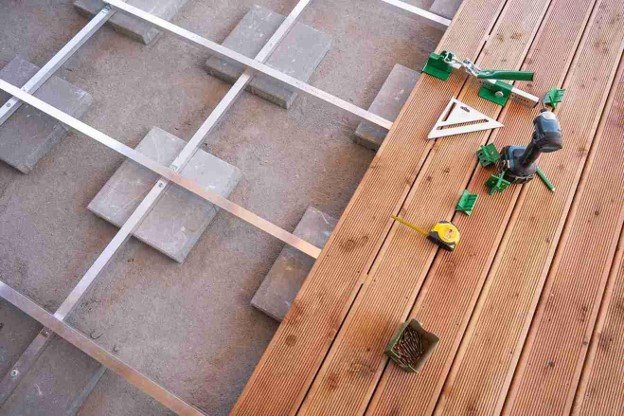 Contractor installing composite Trex deck boards over a metal frame during deck construction